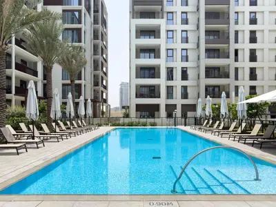 a swimming pool with chairs and umbrellas next to a building at GuestReady - Coastal Style l 2Bed l Lagoon Escape in Dubai