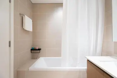 a bathroom with a tub and a shower curtain at GuestReady - Coastal Style l 2Bed l Lagoon Escape in Dubai