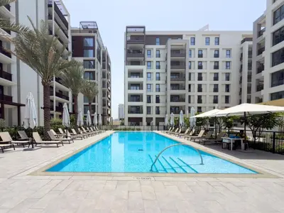 a swimming pool with chairs and umbrellas and buildings at GuestReady - Coastal Style l 2Bed l Lagoon Escape in Dubai