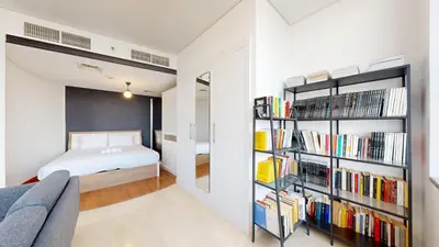 a bedroom with a bed and a book shelf with books at Sky Gardens - High Rise Studio with Cityscape View in Dubai