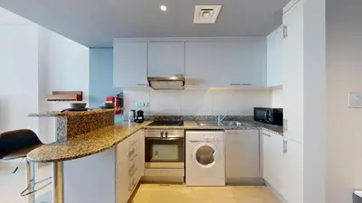 a kitchen with white cabinets and a washing machine at Sky Gardens - High Rise Studio with Cityscape View in Dubai