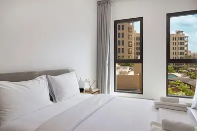 a white bedroom with a large bed and a window at StayMada - Lamtara Near Burj AlArab Beach Access in Dubai