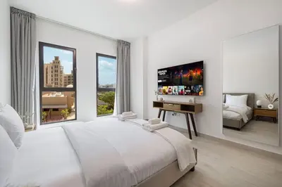a white bedroom with a large bed and a desk at StayMada - Lamtara Near Burj AlArab Beach Access in Dubai