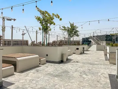 a rooftop patio with tables and benches on a building at VayK - Modern 2BR with Pool View in Sobha Hartland in Dubai