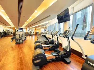 a gym with rows of treadmills and a flat screen tv at PVH - Burj Khalifa View Studio - Emaar Residence Fashion Avenue in Dubai