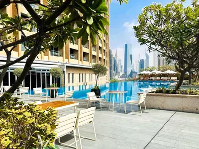 a hotel patio with tables and chairs and a pool at PVH - Burj Khalifa View Studio - Emaar Residence Fashion Avenue in Dubai