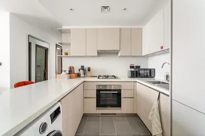 an open kitchen with white cabinets and appliances at Luxury 2BR in Sobha Hartland in Dubai