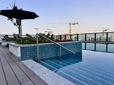 a swimming pool with an umbrella next to a building at Luxury 2BR in Sobha Hartland in Dubai