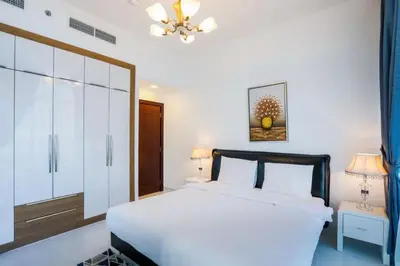 a bedroom with a large white bed and a chandelier at Modern and Spacious 2BR in Glamz, Al Furjan in Dubai