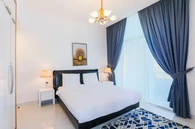 a bedroom with a bed with blue curtains and a window at Modern and Spacious 2BR in Glamz, Al Furjan in Dubai