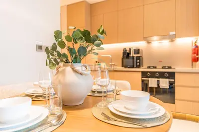 a table with plates and cups and a vase on it at Luxury 1BR Stay, Connected to Dubai Mall and Burj Khalifa, Vida Dubai Mall Tower 2, Downtown Dubai by Deluxe Holiday Homes in Dubai