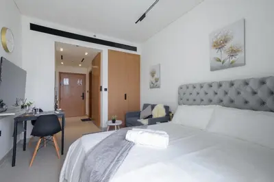 a bedroom with a large white bed and a desk at Studio JVC I Fully Furnished I Epic Pool in Dubai