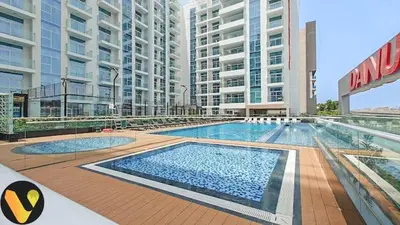 a large swimming pool in front of some tall buildings at Vogue Al Furjan Pearlz by Danube near Ibn Battuta Mall, One Bedroom Apartment with Terrace and vibrant community view, Access to all Amenities, Walkable to Al Furjan Metro Station in Dubai