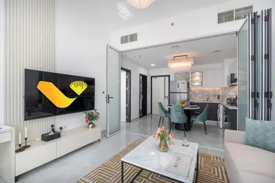 a living room with a couch and a tv on a wall at Vogue Al Furjan Pearlz by Danube near Ibn Battuta Mall, One Bedroom Apartment with Terrace and vibrant community view, Access to all Amenities, Walkable to Al Furjan Metro Station in Dubai