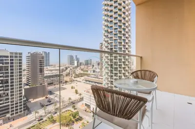 a balcony with a table and chairs and a view of a city at Studio Overlooking the Pool, Close to Parks, Grocery Stores, and Circle Mall, Damac Ghalia, JVC by Deluxe Holiday Homes in Dubai