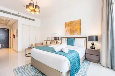 a bedroom with a large bed with a blue blanket at Studio Overlooking the Pool, Close to Parks, Grocery Stores, and Circle Mall, Damac Ghalia, JVC by Deluxe Holiday Homes in Dubai