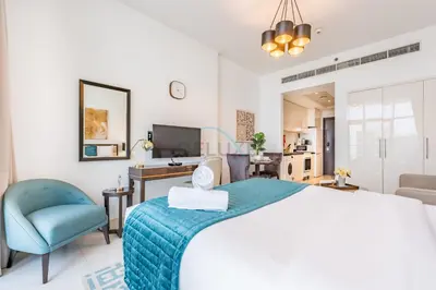 a bedroom with a large bed and a blue chair at Studio Overlooking the Pool, Close to Parks, Grocery Stores, and Circle Mall, Damac Ghalia, JVC by Deluxe Holiday Homes in Dubai