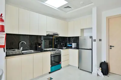 a kitchen with white cabinets and a refrigerator at Stylish 1BR Retreat Huge Balcony in Dubai