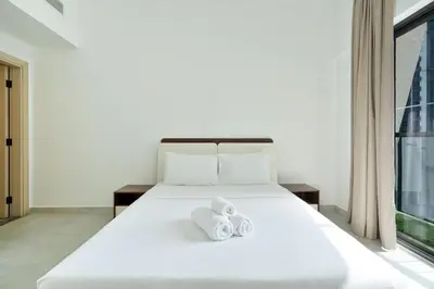 a bedroom with a white bed with towels on it at Stylish 1BR Retreat Huge Balcony in Dubai