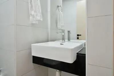a white sink in a white tiled bathroom at Stylish 1BR Retreat Huge Balcony in Dubai