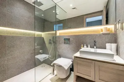 a bathroom with a sink and a glass shower at Cozy Studio with Peaceful Community Views, Just Steps from Parks and Circle Mall, Oxford 212, JVC by Deluxe Holiday Homes in Dubai