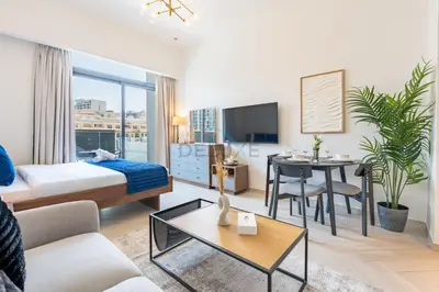 a hotel room with a bed and a table at Cozy Studio with Peaceful Community Views, Just Steps from Parks and Circle Mall, Oxford 212, JVC by Deluxe Holiday Homes in Dubai