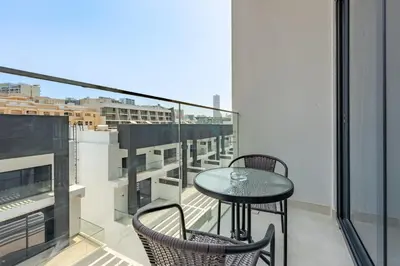 a table and chairs on a balcony with a view at Cozy Studio with Peaceful Community Views, Just Steps from Parks and Circle Mall, Oxford 212, JVC by Deluxe Holiday Homes in Dubai