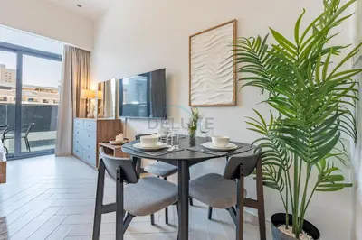 a dining room with a table and a plant at Cozy Studio with Peaceful Community Views, Just Steps from Parks and Circle Mall, Oxford 212, JVC by Deluxe Holiday Homes in Dubai