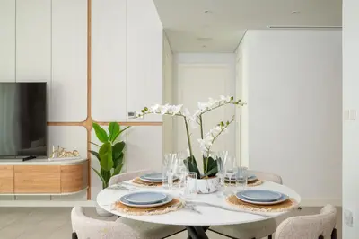 a white dining room with a table with blue and white plates at Beach Please in Dubai