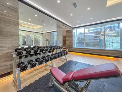 a gym with a bench and lots of dumbbells at Walking Distance to Bay Avenue Mall, 5 Minutes Drive to Downtown Dubai, Close to Metro Station, With Canal View, The Cosmopolitan, Business Bay by Deluxe Holiday Homes in Dubai