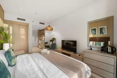 a bedroom with a large bed and a television at Seven Palm Studio Roof Top Pool Beach Gym for free in Dubai