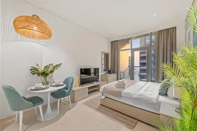 a bedroom with a bed and a table and chairs at Seven Palm Studio Roof Top Pool Beach Gym for free in Dubai
