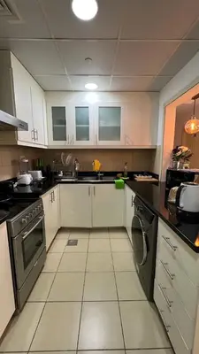 a kitchen with white cabinets and black counter tops at Expedite Homes in Dubai