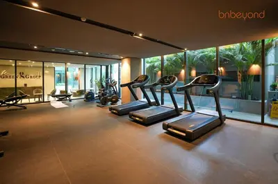 a gym with several tread machines in a room with windows at The Autograph-Art Meets Comfort in Dubai
