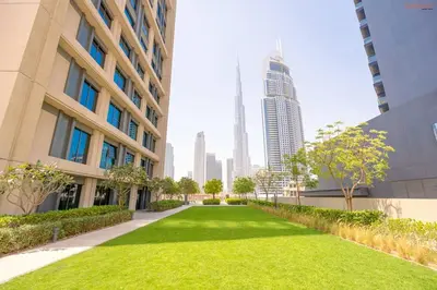 a green lawn between two buildings in a city at Burj Khalifa Light Show from your Bed in Dubai