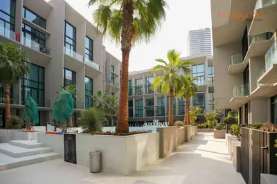 a building with palm trees in a courtyard at Signature Stay at The Autograph in Dubai