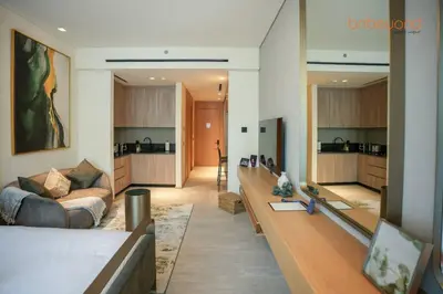 a living room with a couch and a kitchen at Signature Stay at The Autograph in Dubai