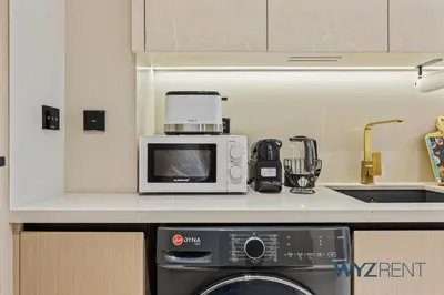 a kitchen with a microwave and a dishwasher at Boho Grecian Studio in JVC Pool & Gym Access in Dubai