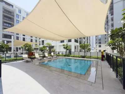 a large umbrella over a swimming pool in a building at GuestReady - 1Bed l Lagoon Escape l Creek Beach in Dubai