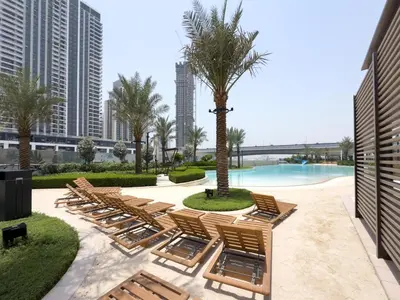 a row of chaise lounge chairs and a pool at GuestReady - 1Bed l Lagoon Escape l Creek Beach in Dubai