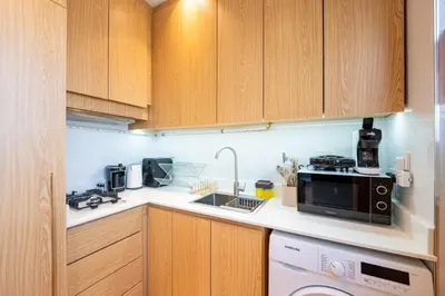 a kitchen with wooden cabinets and a sink and a microwave at Luxury Studio JVC Open View in Dubai