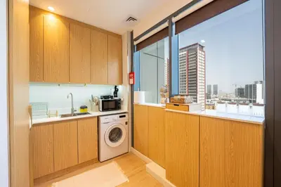 a kitchen with a washing machine and a window at Luxury Studio JVC Open View in Dubai