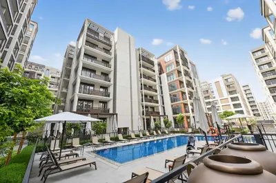 an apartment with a swimming pool and some buildings at Modern 3BD with Maid's Room near Lagoon at Lotus 4 in Dubai