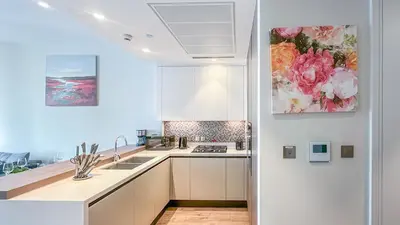 a kitchen with white cabinets and a sink and a painting at Exclusive 1BR in Marina Gate Dubai Marina - 46AB03 in Dubai