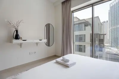 a bedroom with a white bed and a large window at GuestReady - Blue Bliss l 2Bed l Lagoon Escape in Dubai