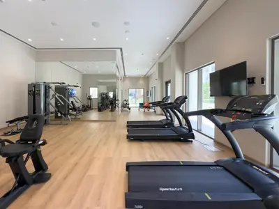a gym with several treadmills and cardio machines at GuestReady - Blue Bliss l 2Bed l Lagoon Escape in Dubai