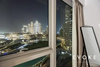 a window with a view of a city at night at Grande Residence Burj View 2 BR by Evoke Luxury in Dubai