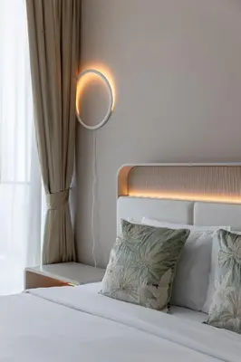 a bedroom with a white bed with a lamp and a mirror at Cozy Studio in JVC Dubai in Dubai