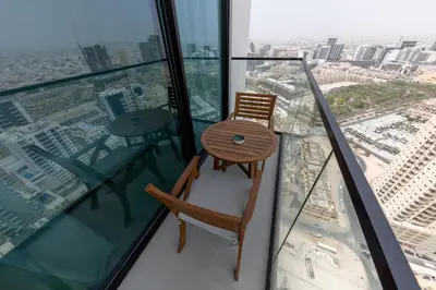 a wooden chair sitting on top of a glass balcony at Cozy Studio in JVC Dubai in Dubai