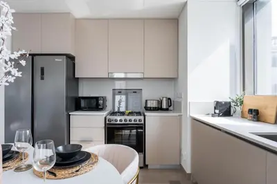 a kitchen with white cabinets and a table with wine glasses at GuestReady - 2Bed l Lagoon Escape l Creek Beach in Dubai